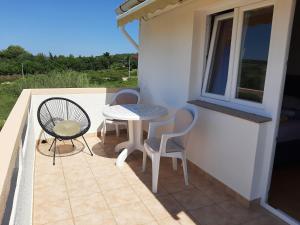 a patio with a table and chairs on a balcony at Apartments Donadic I, Caska in Novalja