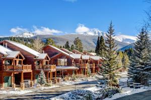 a log cabin in the snow with mountains in the background at Luxury Slopeside Condo #97A Next to Ski Resort With Hot Tub & Great Views - 500 Dollars Of FREE Activities & Equipment Rentals Daily in Winter Park