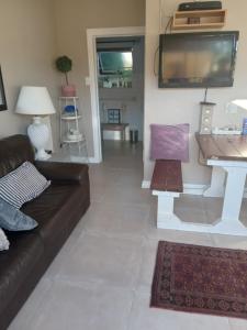 a living room with a couch and a tv at Toscana Cottage in Port Elizabeth