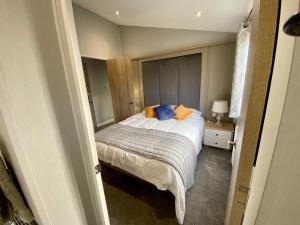 1 dormitorio con 1 cama con almohadas de color naranja y azul en ELITE BLUE LUXURY 3 BEDROOM LODGE NEWQUAY, CORNWALL, en Newquay