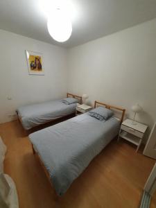two beds in a room with two tables and a lamp at Maison Les Pins in Aigues-Mortes