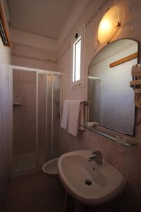 ein Bad mit einem Waschbecken, einem Spiegel und einer Dusche in der Unterkunft Hotel Roma in Lido di Jesolo