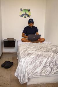 um homem sentado numa cama com um portátil em Hostería Poza Rica em Poza Rica de Hidalgo