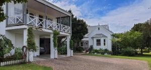 a white house with a balcony on the side of it at Belvidere102 in Knysna