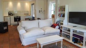 a living room with a white couch and a flat screen tv at Belvidere102 in Knysna