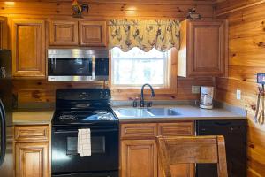a kitchen with a stove and a sink and a microwave at Black Bear Hideaway Cabin in Gatlinburg