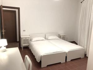 een wit bed in een witte slaapkamer met 2 tafels bij Casa Lauretana in Loreto