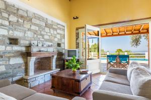 a living room with a stone fireplace and a tv at Villa Jasmine - Peaceful Sunset View Retreat in Skopelos Town