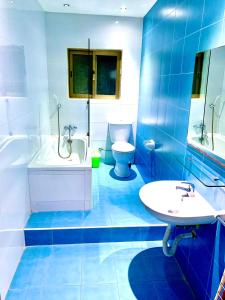 baño azul y blanco con bañera y lavamanos en Paceville Apartments en St Julian's