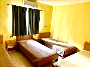 a room with two beds and a window with curtains at Paceville Apartments in St. Julianʼs