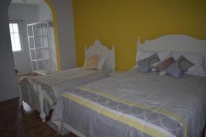 two beds in a bedroom with yellow walls at Villa Vicente in Vila Nova Sintra