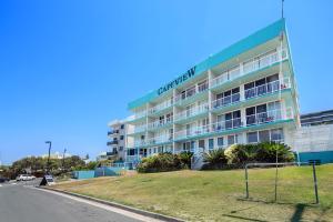 a building with a soccer field in front of it at Capeview Apartments - Right on Kings Beach in Caloundra
