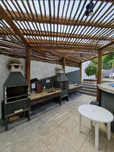 a patio with an outdoor kitchen with a wooden pergola at Afras Maresias in Sao Paulo