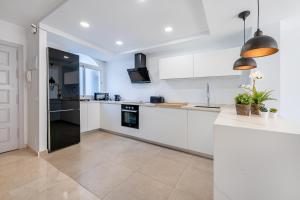 cocina con armarios blancos y nevera negra en Precioso apartamento en el centro con aparcamiento en Málaga