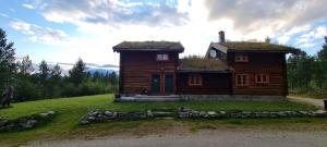 a log cabin with a grass roof on a field at Øvre Nordli Rondane Utleie Sollia Friluftsliv in Sollia