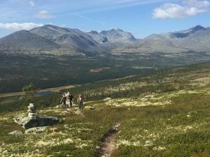 a group of people walking on a hill with mountains in the background at Rondane Sollia Friluftsliv Øvre Nordli in Sollia +47 photos