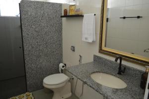 a bathroom with a toilet and a sink and a mirror at Casa aconchegante em Guapé, Lago de Furnas. in Guapé +26 photos