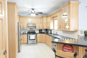 a kitchen with wooden cabinets and a ceiling fan at PlanURstay - Carrying Place 6BR & 3BTH Near SandBanks Park in Carrying Place