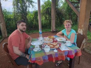 un hombre y una mujer sentados en una mesa con comida en Sigiriya Paddy Field Hut, en Sigiriya
