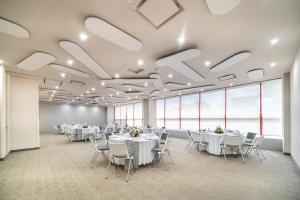 a conference room with white tables and chairs and large windows at Metria Hotel in León