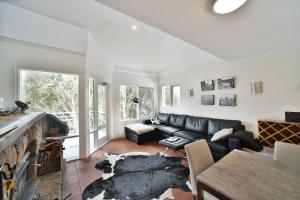 a living room with a black leather couch at Inala 3 in Thredbo