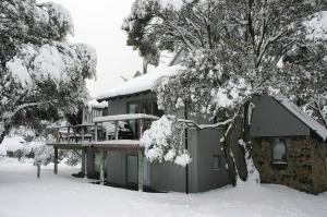a house covered in snow with a building at Jagungal in Thredbo