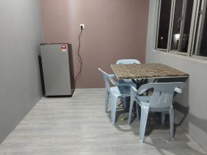 グア・ムサンにあるAlish Homestay Gua Musang with Free WiFi, Netflixのテーブルと椅子、冷蔵庫が備わる客室です。