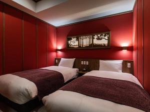 two beds in a room with red walls at La Vista Kusatsu Hills in Kusatsu