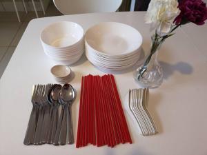 una mesa con tenedores y platos y un jarrón con flores en W5WarmStay@Golden Hill/Penthouse/WiFi/3R/NightMarket/2CarPark, en Brinchang