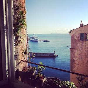 a window with a view of a boat in the water at CASA MANTINUM au coeur de la Citadelle in Bastia
