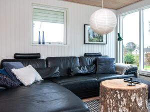 エーベルトフトにある8 person holiday home in Ebeltoftのリビングルーム(黒い革張りのソファ、テーブル付)