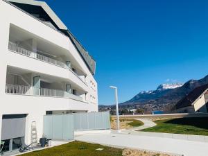 a white apartment building with mountains in the background at A la belle quatrième étoile in Annecy