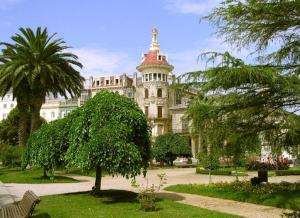 Un gran edificio con una palmera delante. en Escuder Apartamentos Turísticos, en Ribadeo
