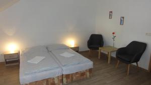 a bedroom with a bed and two chairs and a table at Penzion U Hradeb in Znojmo