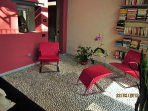 a living room with two red chairs and a book shelf at Casetta delle Rose in Biella