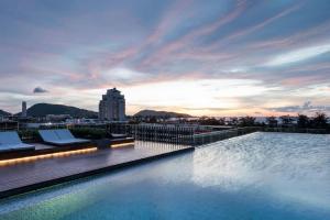 a large swimming pool on a building with a sunset at The Deck patong Luxury Apartments The Deck patong in Patong Beach