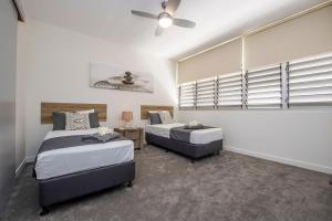 a bedroom with two beds and a ceiling fan at Bright Point 1308 at Magnetic in Nelly Bay