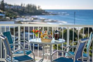 a table and chairs on a balcony with a view of the ocean at Capeview Apartments - Right on Kings Beach in Caloundra