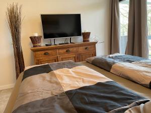 a bedroom with two beds and a television on a dresser at Moderne Ferienwohnung / Top City- u. Wasserlage am Yachthafen Bad Zwischenahn in Bad Zwischenahn