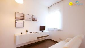 een witte woonkamer met een tv aan de muur bij Mango 2 Pineto Vacanza in Pineto