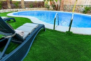a pool with a chair next to a swimming pool at Villa Yotam 4BR Heated pool וילה יותם 4 חדרי שינה בריכה מחוממת in Eilat