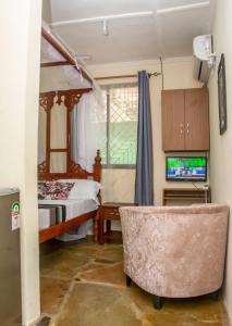 um quarto com uma cama, uma cadeira e uma televisão em Amarossi Rhino-Studio Terrace Apartment,Mtwapa em Mtwapa
