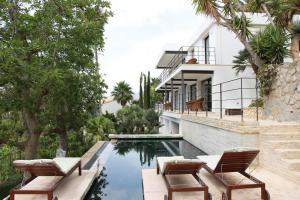 una piscina con due sedie e una casa di El jardin Botánico Villa LUZ ad Altea