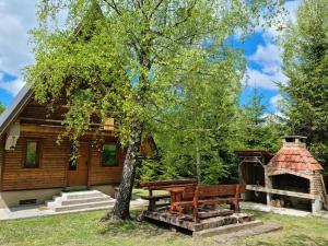 a wooden cabin with a picnic table and a tree at Holiday Home Edi in Delnice