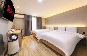 um quarto de hotel com duas camas e uma televisão de ecrã plano em LABE Hotel em Jeonju
