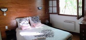 1 dormitorio con 1 cama con almohadas rosas y blancas en Gîte nature détente pêche baignade dans lac privé, en Saint-Martin-des-Combes