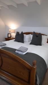 um quarto com uma cama de madeira com lençóis e almofadas brancos em The Dookit - Aviemore Town House em Aviemore