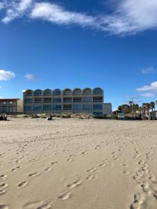 um edifício na praia com pegadas na areia em Superbe Studio Rénové les pieds dans l'eau! em Marseillan