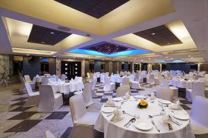 a banquet hall with white tables and white chairs at Radha Regent, Chennai in Chennai