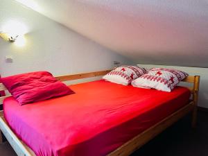 Una cama con almohadas rojas y blancas. en Les Menuires skis aux pieds en Les Menuires